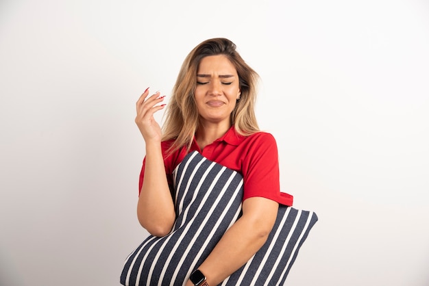 Woman in red shirt hugging a pillow on white background.