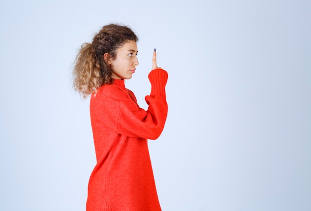 woman in red shirt pointing at somebody or somewhere with emotional face on blue. 