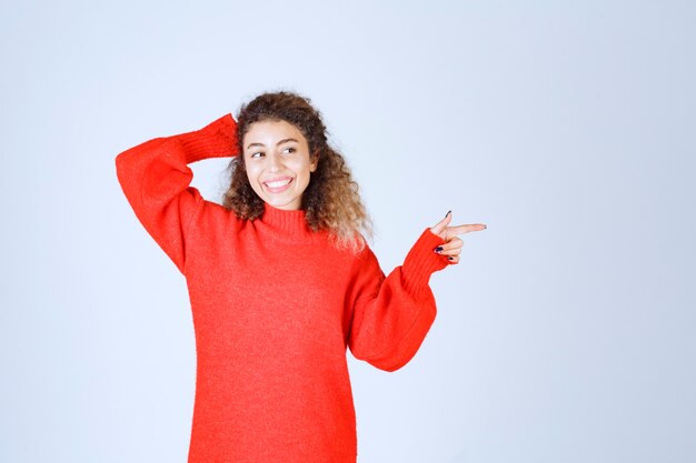 woman in red shirt pointing at somebody or somewhere with emotional face on blue