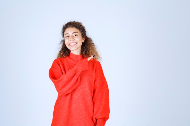 woman in red shirt pointing at somebody or somewhere with emotional face on blue