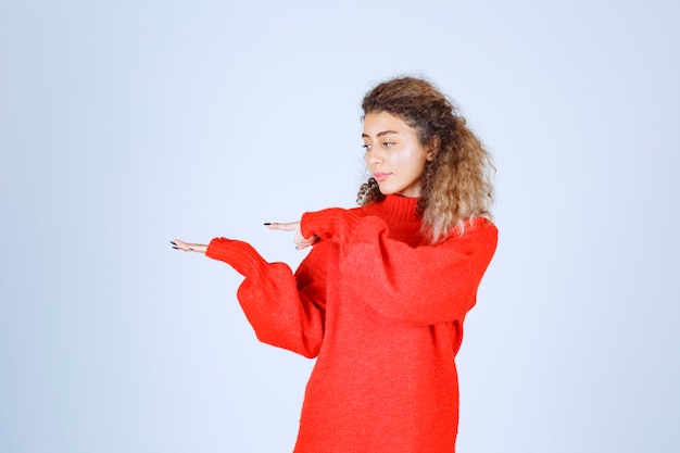 Donna in camicia rossa che indica qualcosa a sinistra.