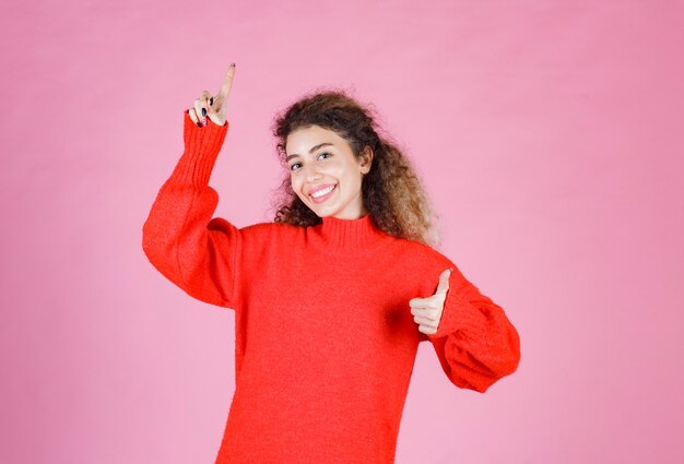 woman in red shirt showing like hand sign. 