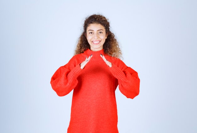 woman in red shirt showing roof sign. 