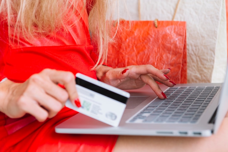 Free Photo woman in red sitting with laptop and card near shopping bags 
