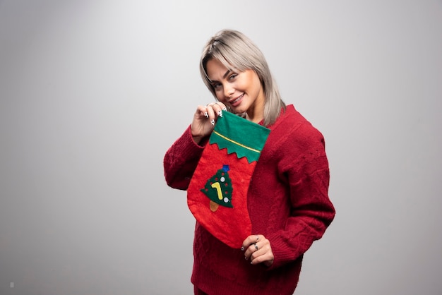 Woman in red sweater posing with Christmas stocking.