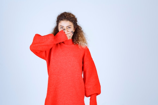 woman in red sweatshirt looking across her fingers. 