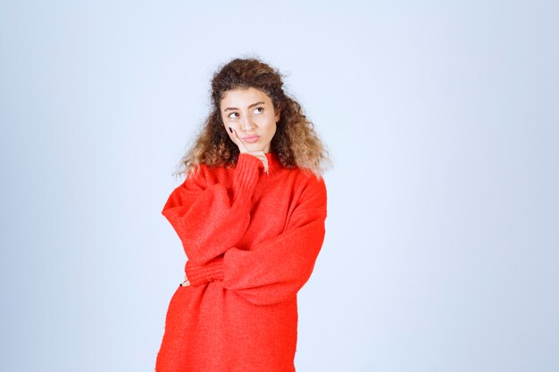 woman in red sweatshirt looks confused and thoughtful. 