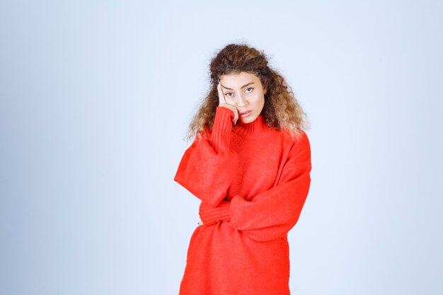 woman in red sweatshirt looks confused and thoughtful. 