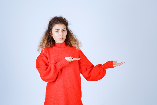 woman in red sweatshirt looks confused and thoughtful. 