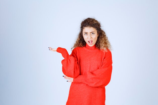 woman in red sweatshirt looks confused and thoughtful. 