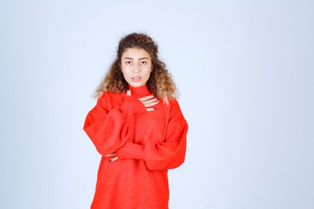 woman in red sweatshirt looks confused and thoughtful. 