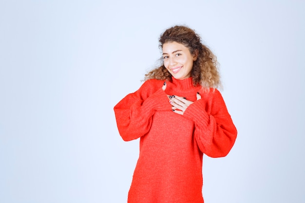 Free photo woman in red sweatshirt pointing at herself.