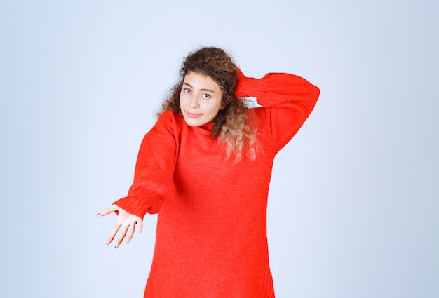 woman in red sweatshirt pointing someone ahead.