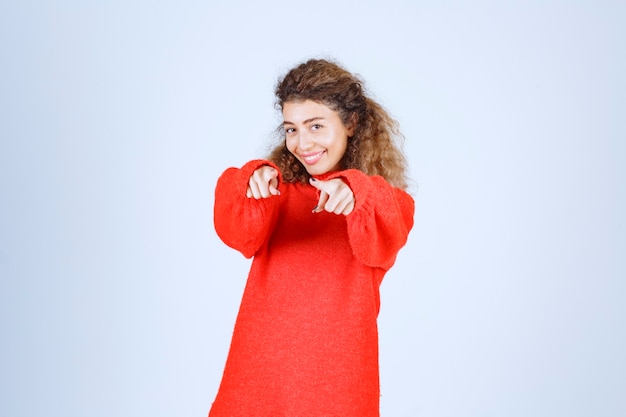 woman in red sweatshirt pointing someone ahead. 