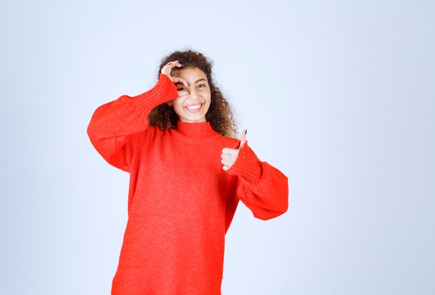 楽しみのサインを示す赤いスウェットシャツの女性。