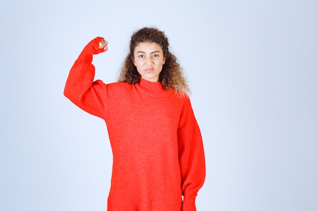 Free photo woman in red sweatshirt showing her fist and meaning her power.