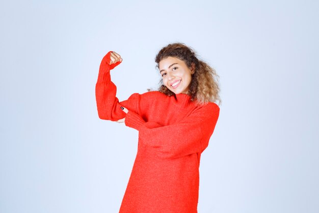 женщина в красном свитере показывает кулак и означает свою силу.