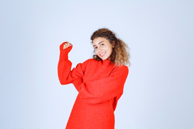 женщина в красном свитере показывает кулак и означает свою силу.