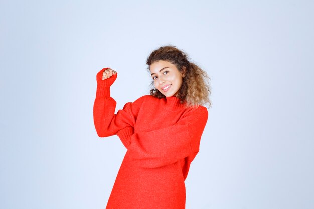 woman in red sweatshirt showing her fist and meaning her power. 