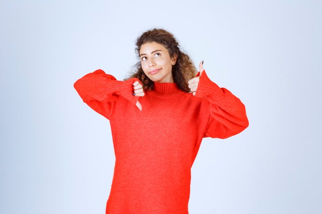 표지판 위아래로 엄지 손가락을 보여주는 빨간색 셔츠에 여자.