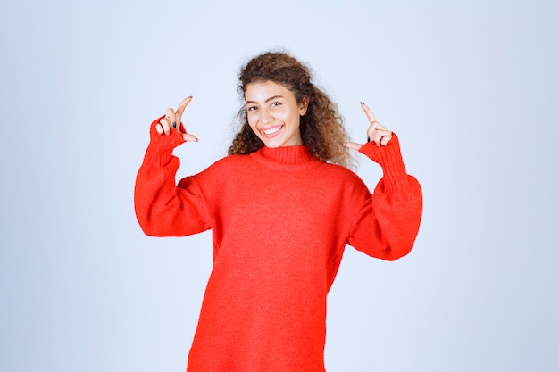 Free photo woman in red sweatshirt showint the measures of an object.