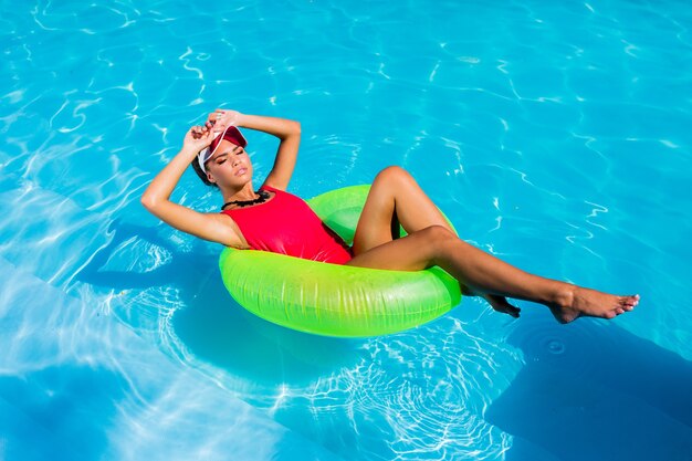 素晴らしい大きなプールで夏を楽しんで楽しんでいる赤い水着の女性。