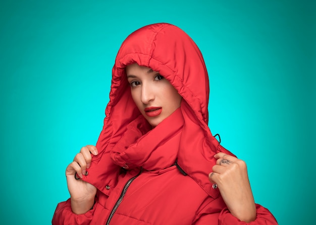 Woman in red winter hooded jacket blue background 