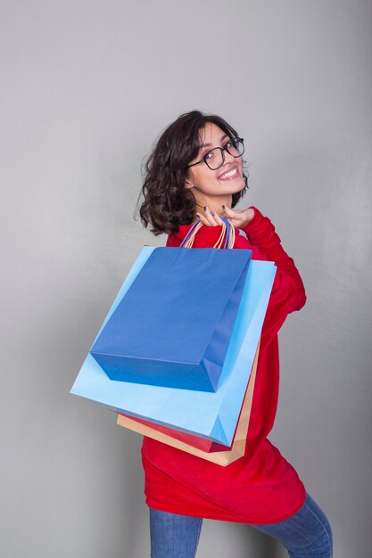 Woman in red with shopping bags behind back 