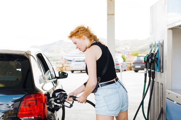 Woman refueling car with gasoline at petrol station