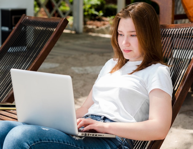 Woman relaxed in chair working on laptop