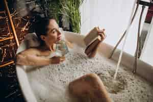 Free photo woman relaxing in bath with bubbles and drinking wine