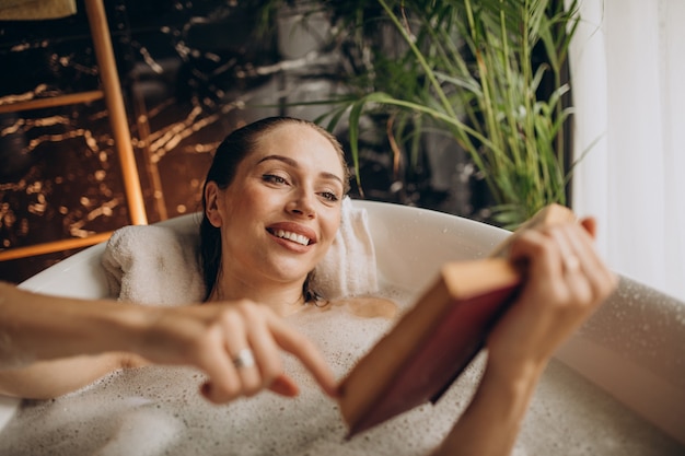 Donna che si distende nella vasca da bagno con le bolle