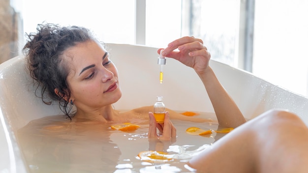 オレンジスライスと浴槽でリラックスする女性