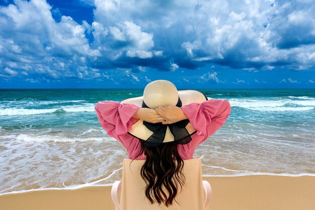 Woman relaxing on deck chair at beach and looking at ocean.