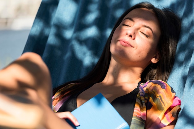 Foto gratuita donna che si distende in amaca mentre in spiaggia con il libro