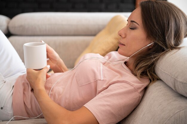Женщина расслабляется дома во время прослушивания музыки
