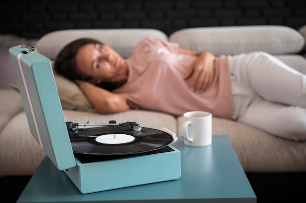 Женщина расслабляется дома во время прослушивания виниловой музыки