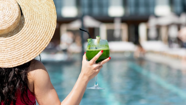 Женщина расслабляющий в бассейне с напитком
