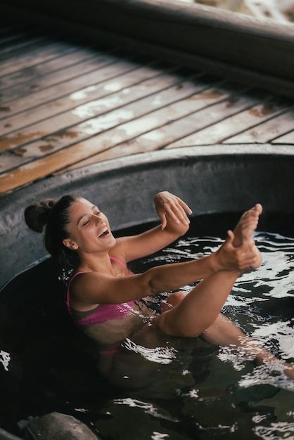 Donna che si rilassa nella vasca da bagno rotonda all'aperto. cura della pelle organica nel bagno caldo nella località termale.