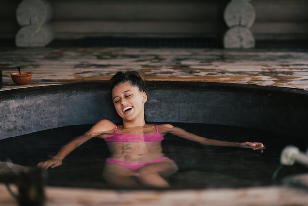 Woman relaxing in round outdoor bath organic skin care in hot bath