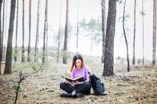 Женщина, расслабляющий с книгой в лесу