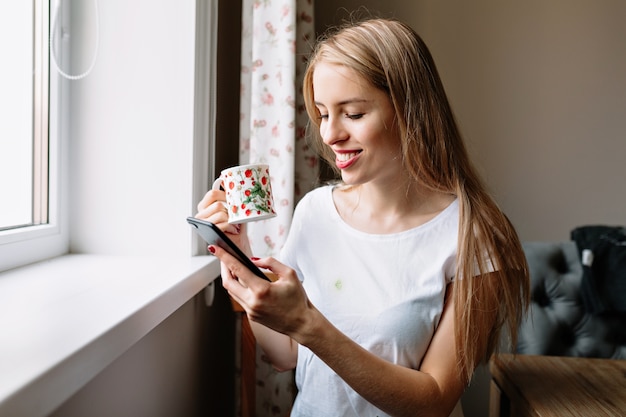 窓際のコーヒーでリラックスする女性