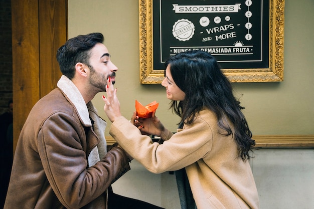 Woman remove crumbs from face of man