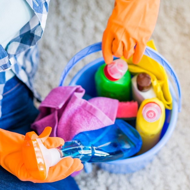 Free photo woman removing cleaner spray bottle from blue bucket