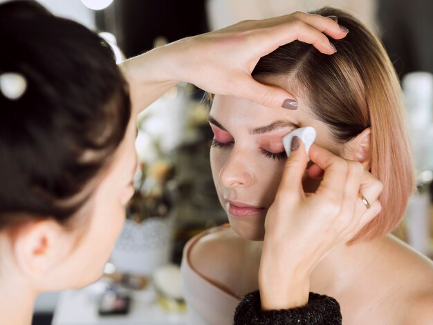 Woman removing eye makeup from model