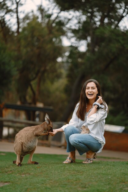 Woman in the reserve is playing with a kangaroo