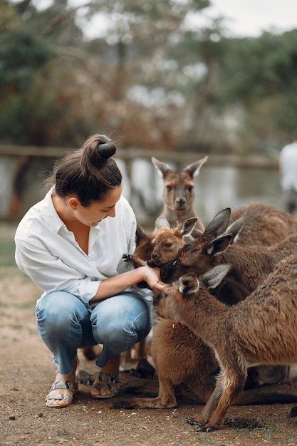 Woman in the reserve is playing with a kangaroo