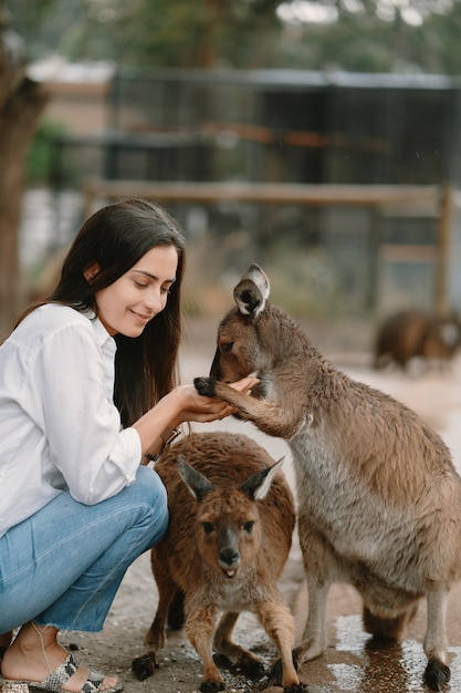 Женщина в заповеднике играет с кенгуру