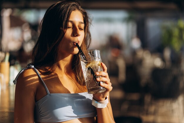 ビーチバーで休んでいる女性がさわやかなカクテルを飲む