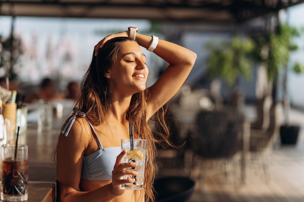 ビーチバーで休んでいる女性はさわやかなカクテルを飲みます